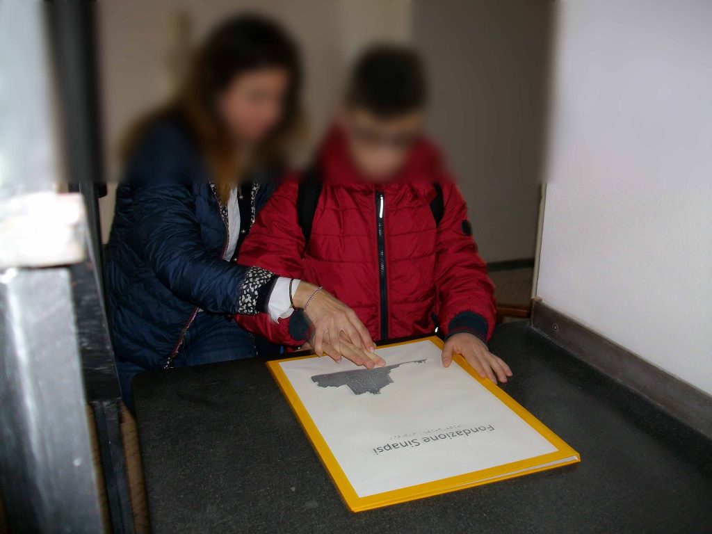 Esplorazione tattile del libro Castello di Baia in nero, in p.i.a.f. e in Braille
