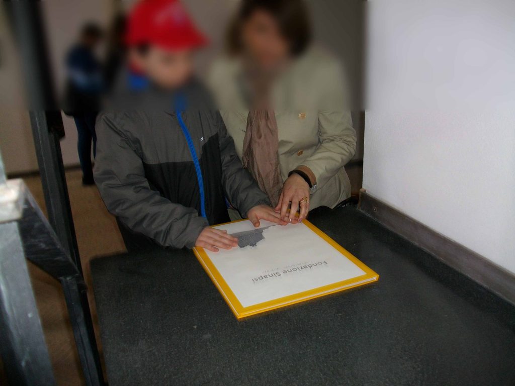 Esplorazione tattile del libro Castello di Baia in nero, in p.i.a.f. e in Braille