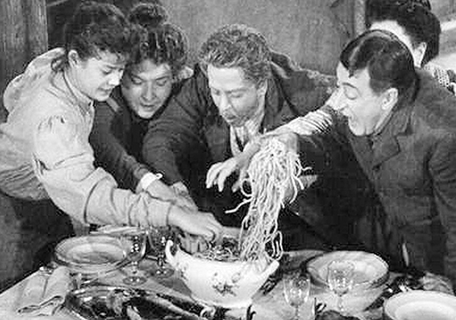 una scena del film miseria e nobiltà: tutti affamati si catapultano su un piatto di spaghetti situato al centro della tavola