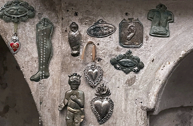 Un dettaglio di una parete nella chiesa di Santa Luciella a Napoli. Sul muro di cemento sono appesi diversi ex-voto