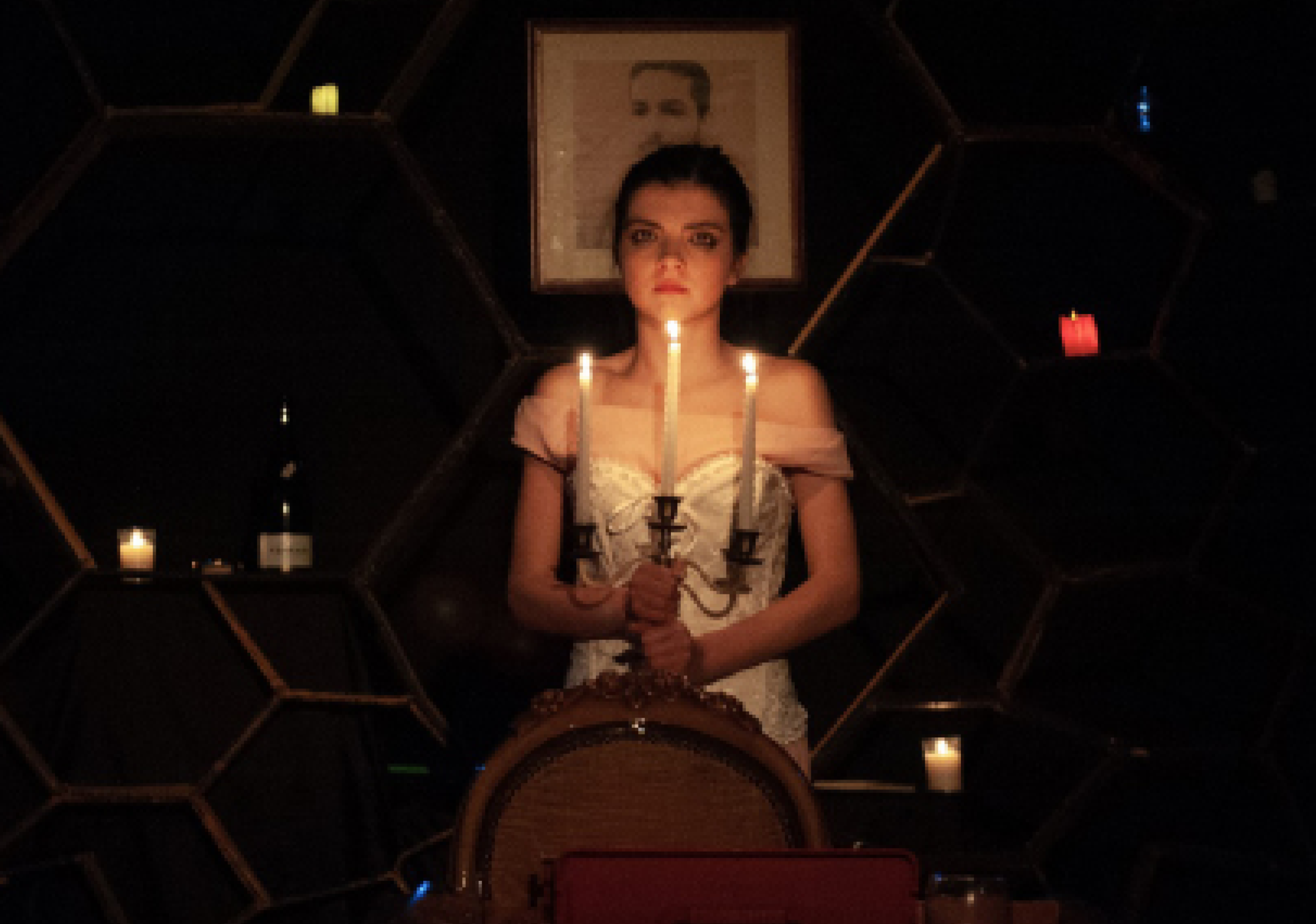 Un’immagine di uno spettacolo teatrale della compagnia NEO. Ragazza al buio con candelabro e candele accese