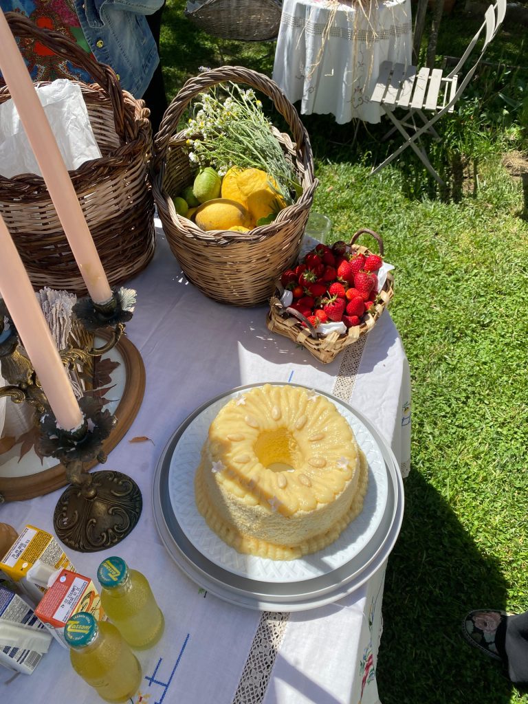 Chiffon cake al limone su un tavolo nell'orto; intorno cestini con fragole, limoni e erbe aromatiche